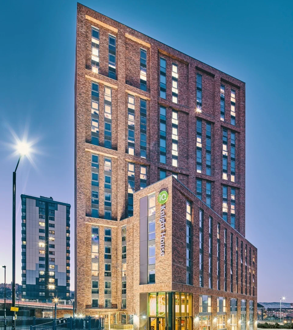Knight House in Sheffield at dusk, showing the brick tower and illuminated ground floor.